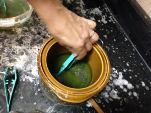 Placing pendants in the acid bath for cleaning